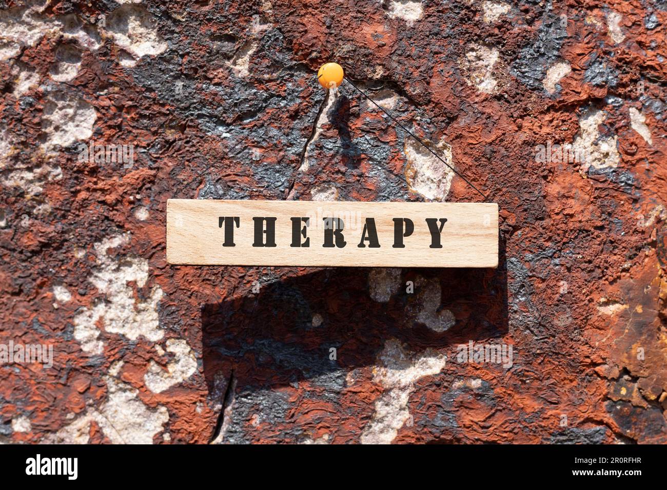 Die Inscription Therapy ist auf einer Holzfläche beschriftet. Felsoberfläche im Freien. Stockfoto