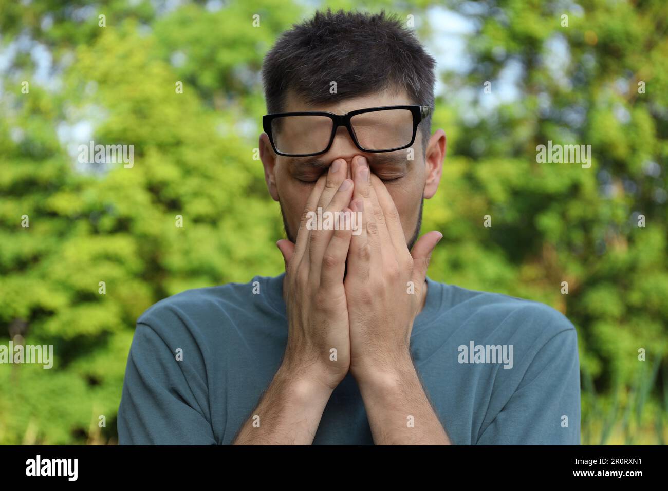 Ein Mann, der an sonnigen Tagen im Freien unter Augenschmerzen leidet Stockfoto