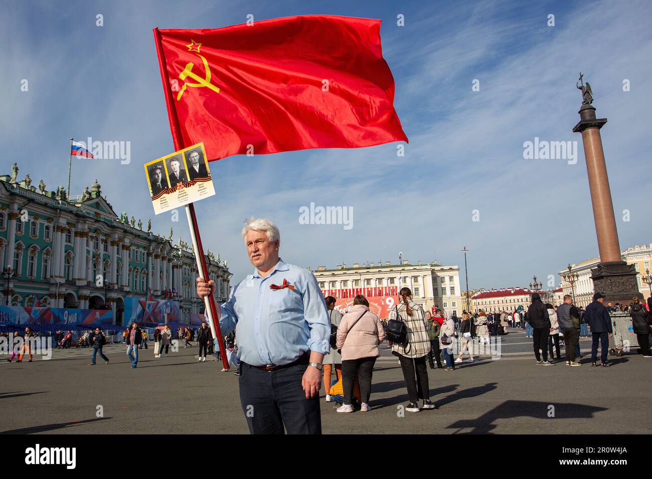 Ein Mann hält eine russische Flagge und Fotos seiner Verwandten
