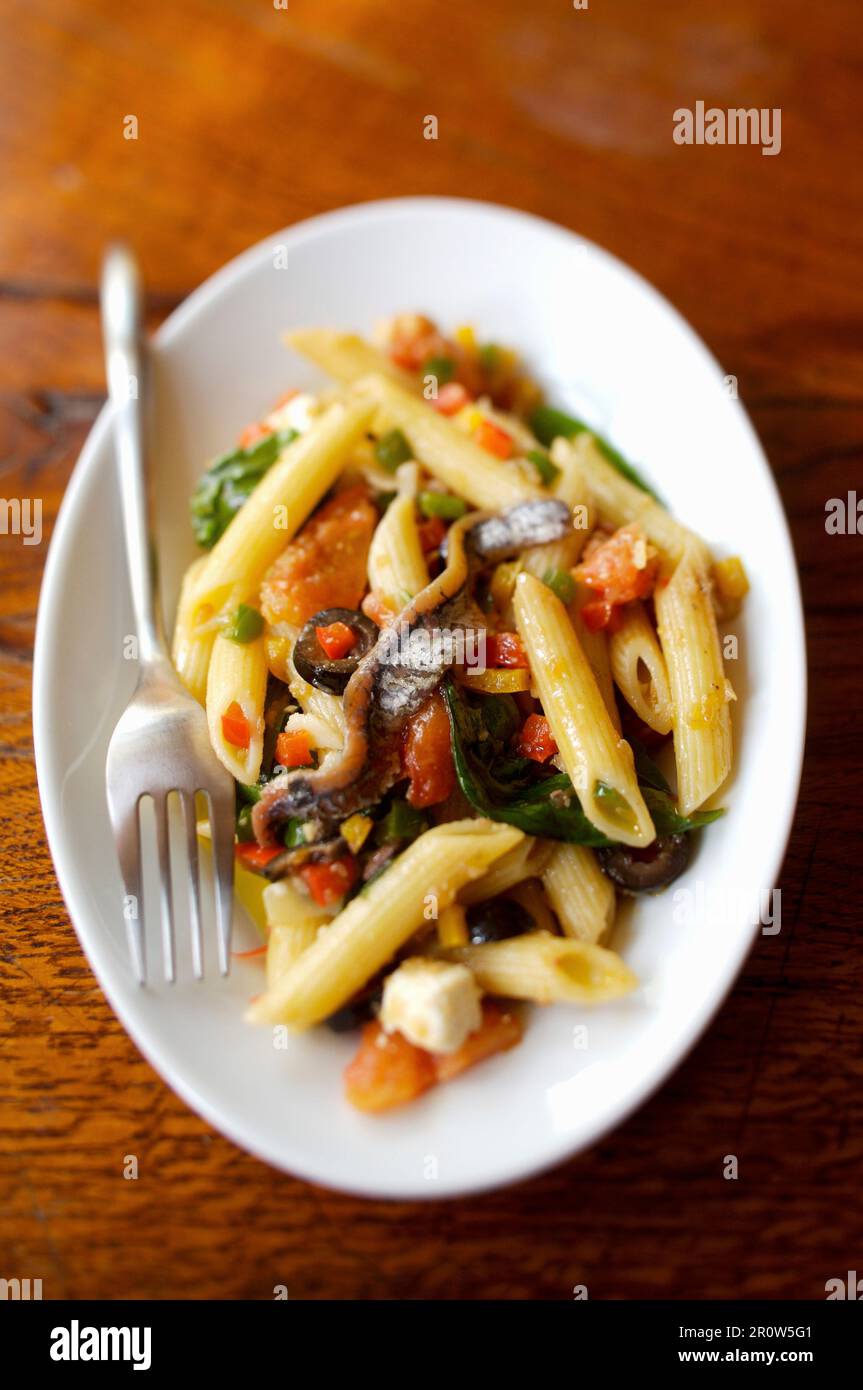 Penne, Sardelle, Pfeffer und Basilikum Stockfoto