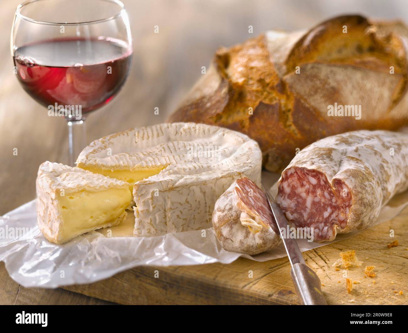 Camembert, getrocknete Wurst, Brot und ein Glas Rotwein Stockfoto