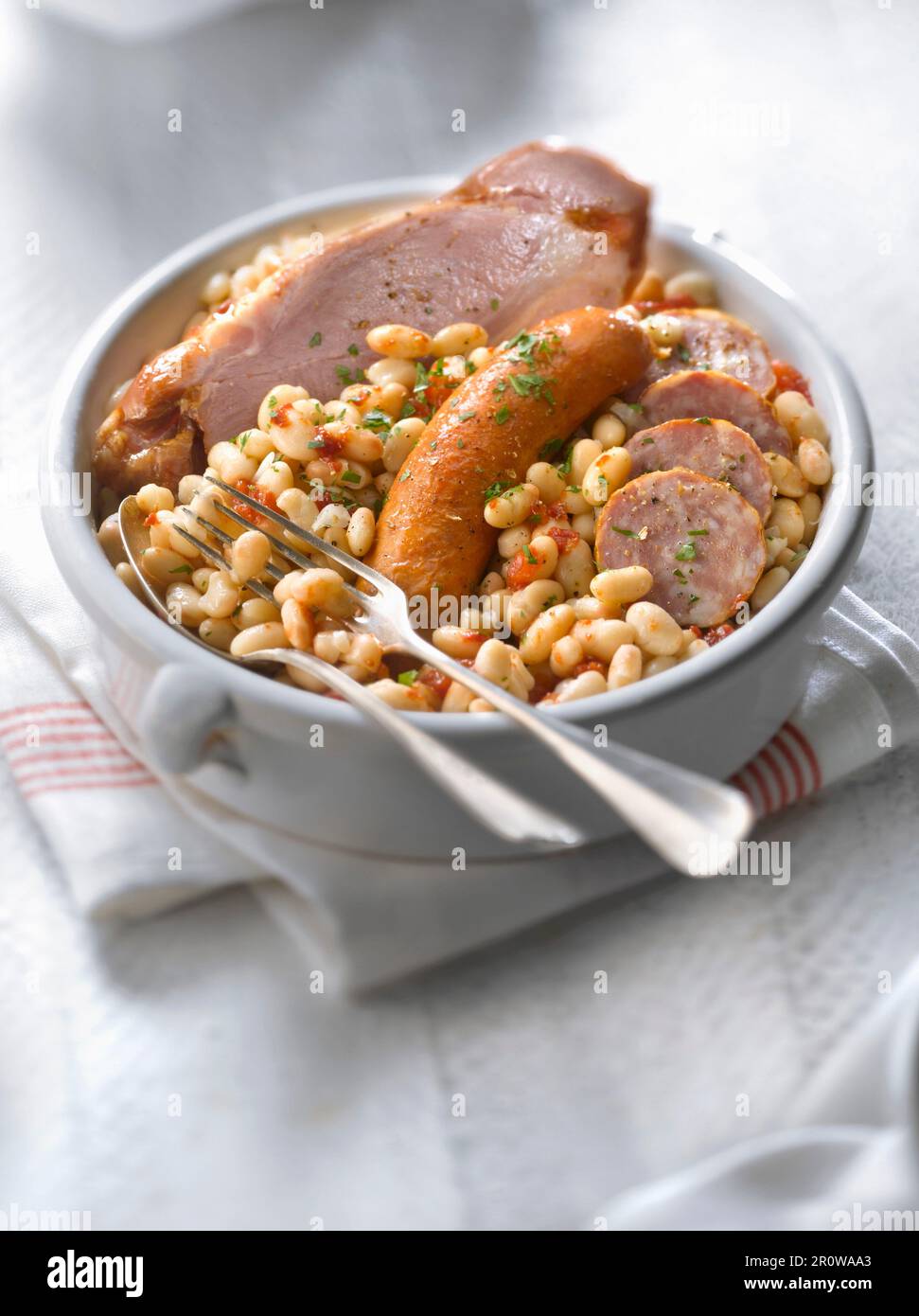 Weiße Bohnen in Tomatensauce mit Schweinesalz und Würstchen Stockfoto