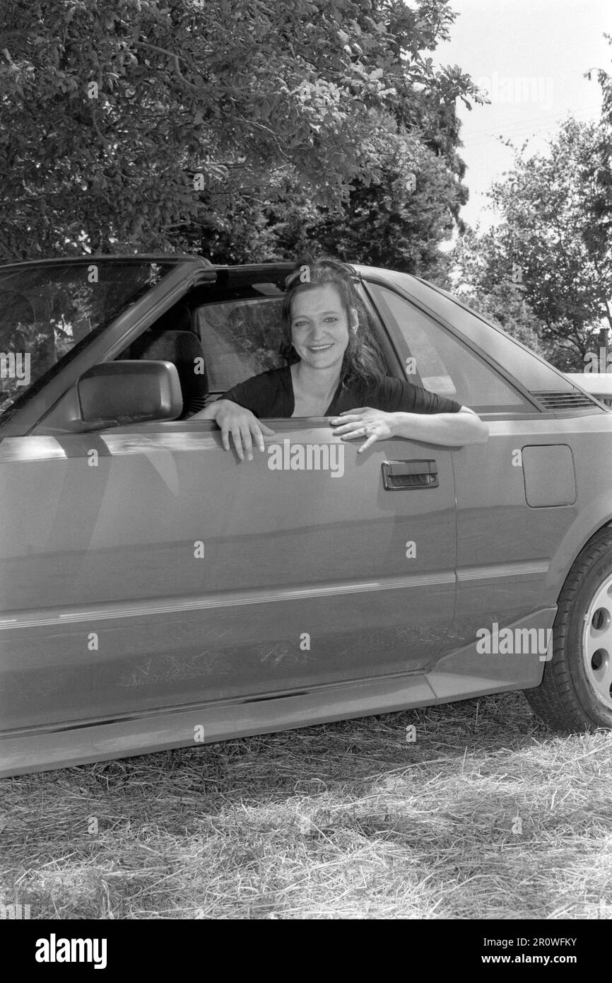 Junge, schlanke, dunkelhaarige Frau, die sich für ein Porträt mit Toyoya-mr2 mk1-t-Riegel-Auto posiert, 1990er england uk Stockfoto