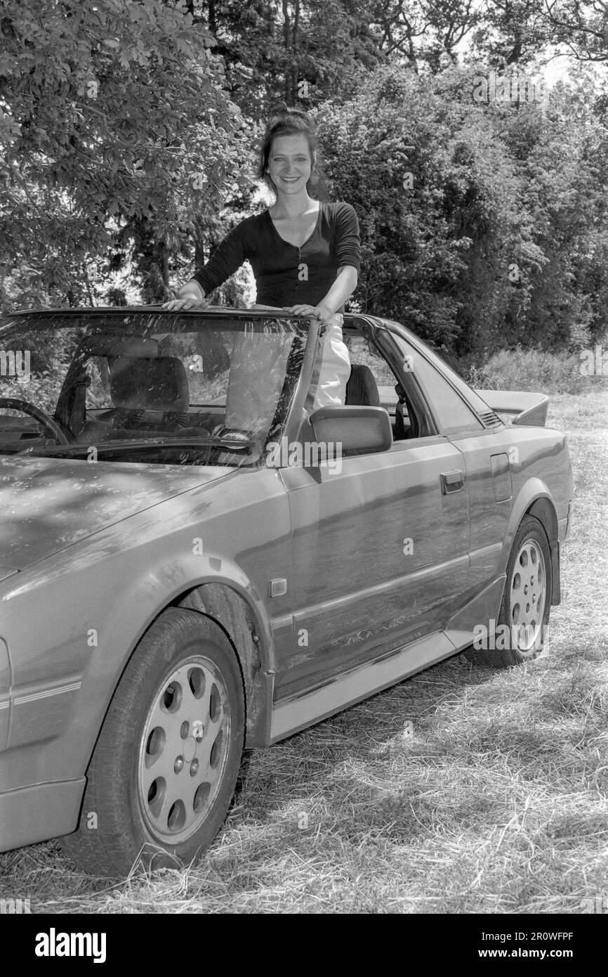 Junge, schlanke, dunkelhaarige Frau, die sich für ein Porträt mit Toyoya-mr2 mk1-t-Riegel-Auto posiert, 1990er england uk Stockfoto
