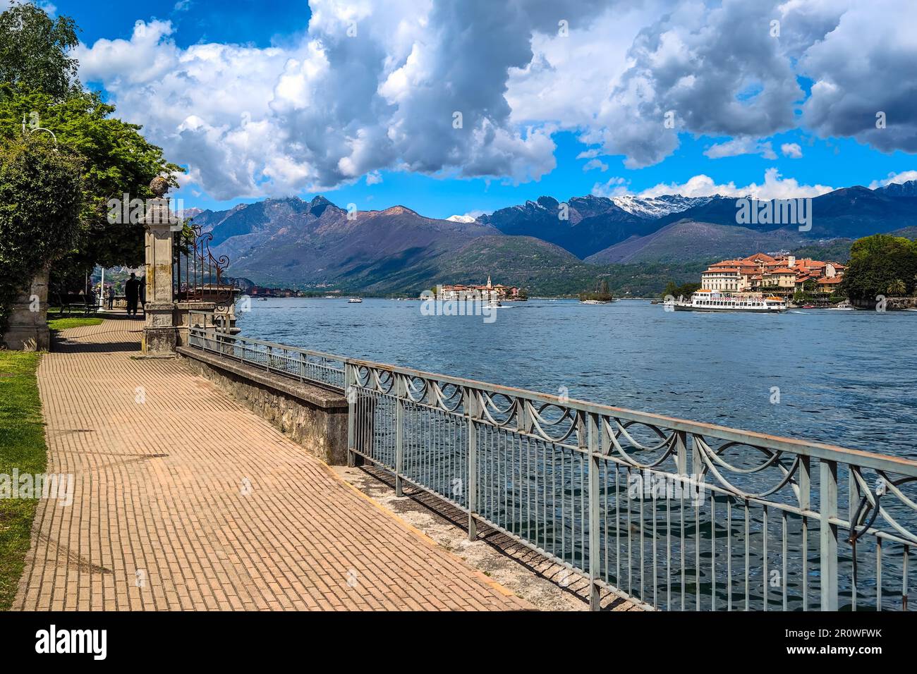 Promenade am Lago Maggiore als kleine Inseln und Berge unter schönem Himmel im Piemont, Norditalien. Stockfoto
