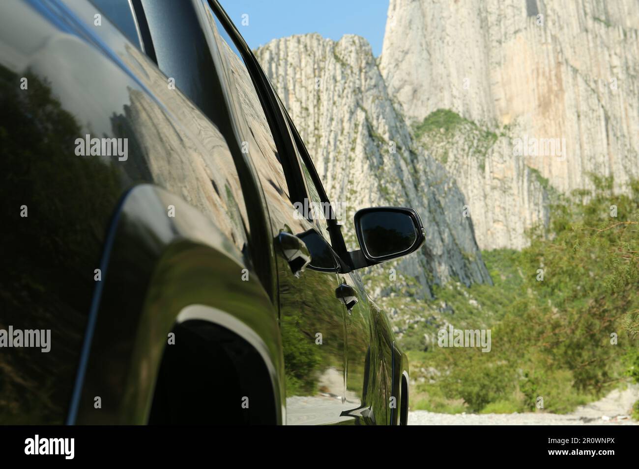Malerischer Blick auf große Berge und Bäume in der Nähe der Straße mit Auto, aus nächster Nähe Stockfoto