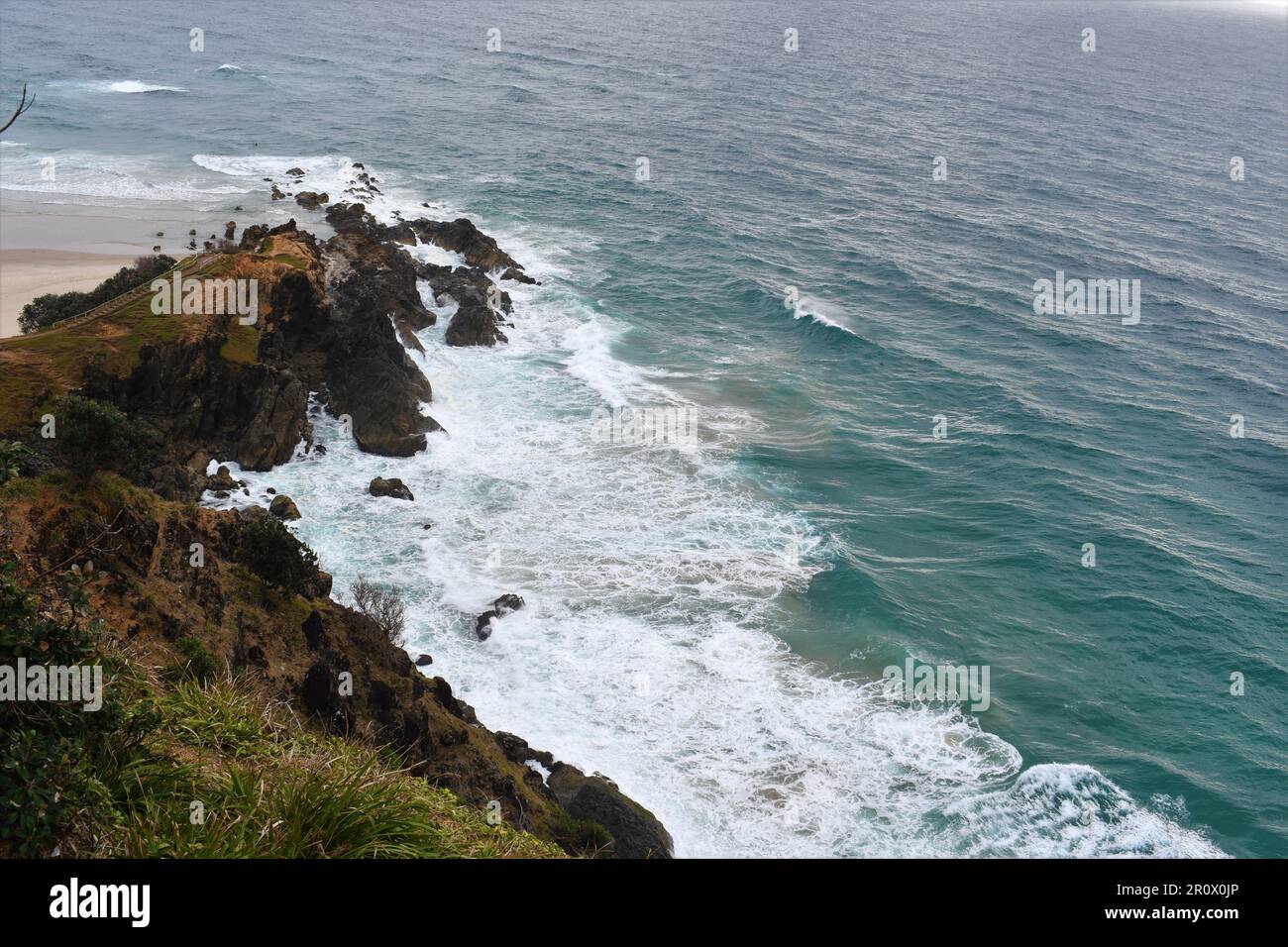 Aus der Vogelperspektive können Sie die wunderschönen Wellen des Ozeans sehen, die auf den felsigen Klippen der Byron Bay-Küste vom Leuchtturm aus stürzen Stockfoto