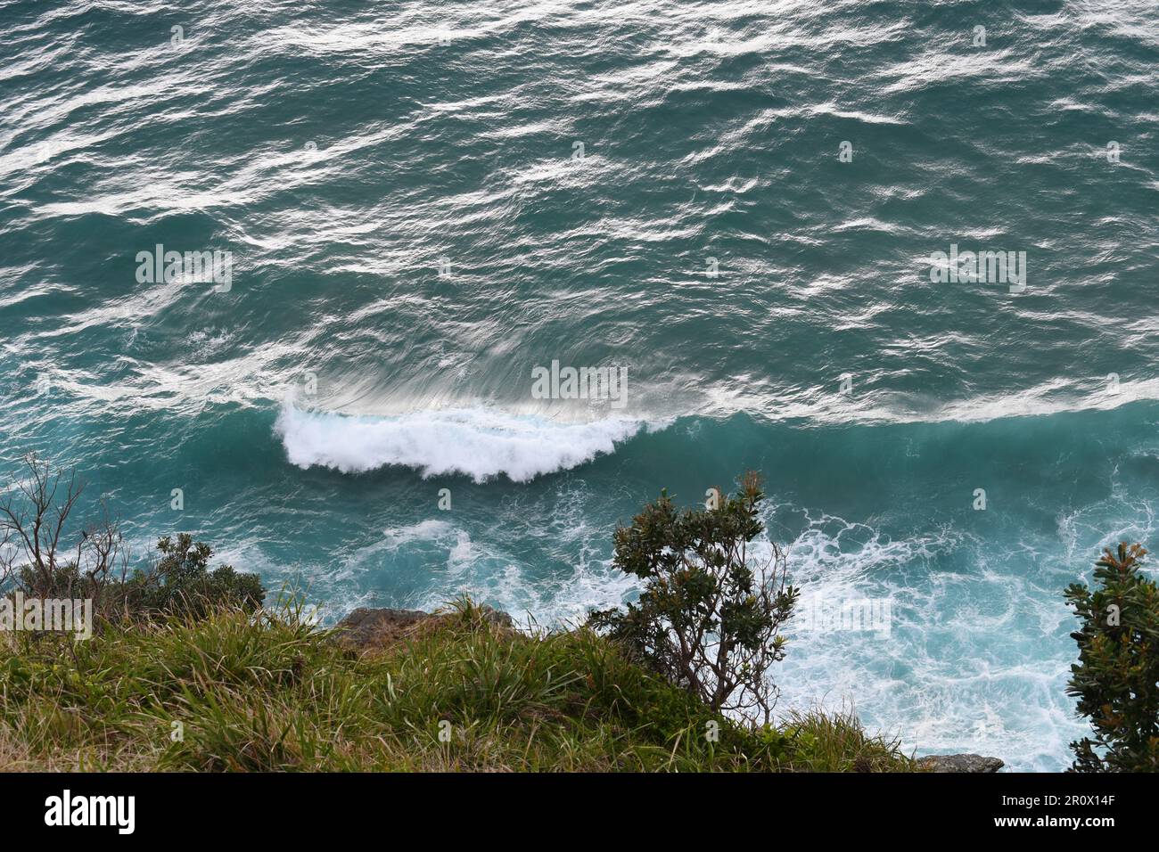 Aus der Vogelperspektive können Sie die wunderschönen Wellen des Ozeans sehen, die auf den felsigen Klippen der Byron Bay-Küste vom Leuchtturm aus stürzen Stockfoto