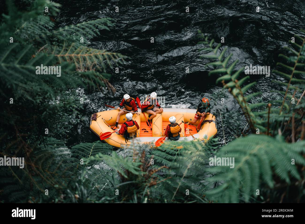 Luftaufnahme von fünf Personen in Badeanzügen und Schwimmwesten mit Rudern in der Hand in einem aufblasbaren Boot bereit, Rafting auf der starken Strömung zu gehen Stockfoto