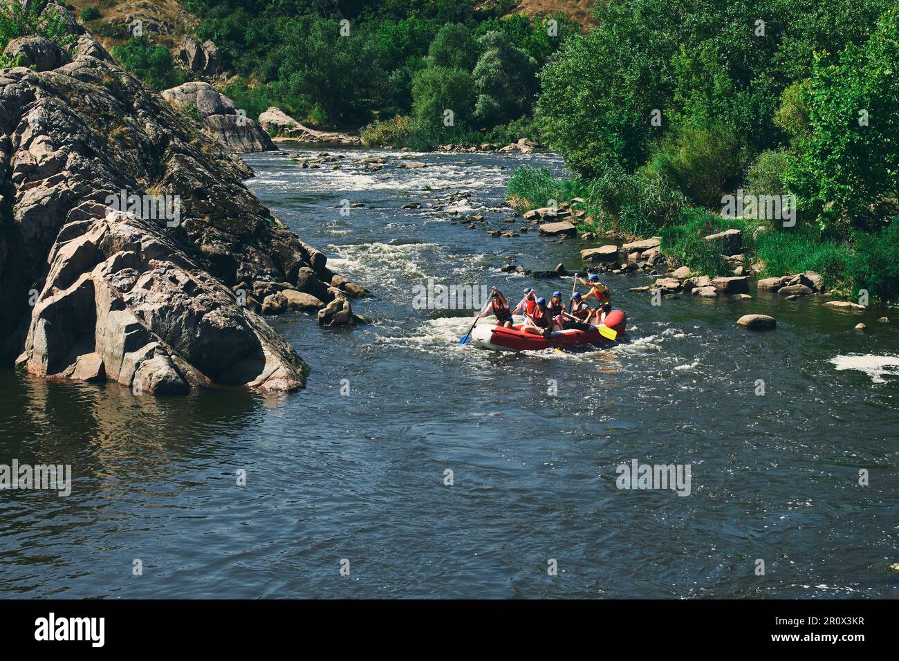 Rafting, Kajakfahren. Extremsport. Wasserökologischer Tourismus. Eine Gruppe von Menschen auf einem aufblasbaren Gummi-Boot auf dem Fluss in der Nähe des Bergwaldes. Stockfoto