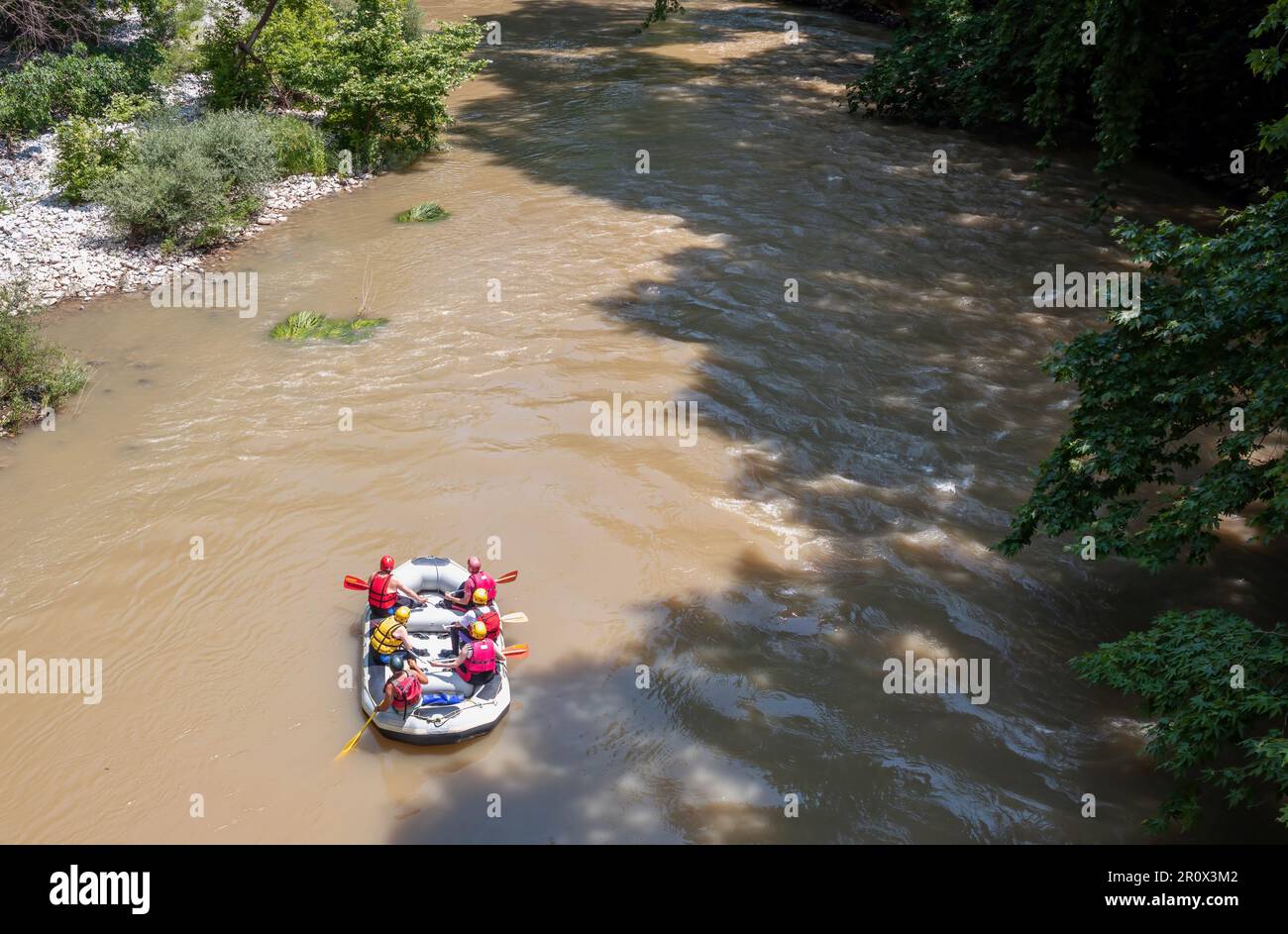 River Rafting in Griechenland Blick von oben. Personen in Sicherheitsausrüstung auf einem Floß, dem braunen Wasser des Pineios River, dem Tal von Tempi, Thessalien Stockfoto