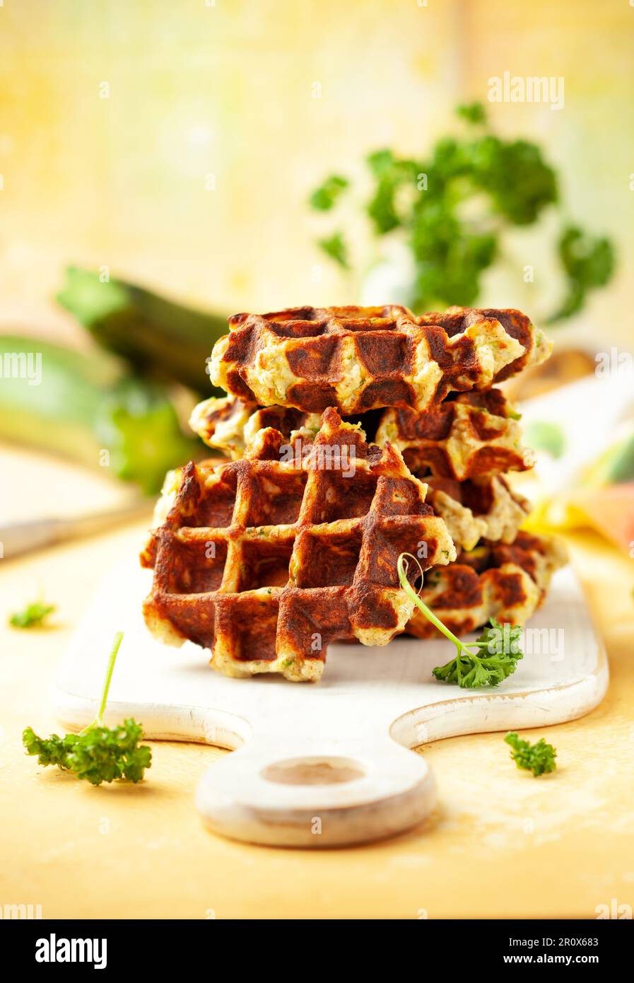 Hausgemachte kohlenhydratarme Zucchini-Waffeln auf weißem Holzbrett auf gelbem Hintergrund. Konzept der Keto-Diät. Stockfoto