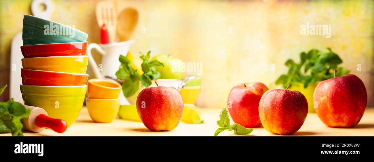 Küchenutensilien und Essenshintergrund mit mehrfarbigen Keramikschüsseln, Rollnadel, Kanne, Sieb, Spatel auf gelbem Hintergrund. Konzept des Heims Stockfoto