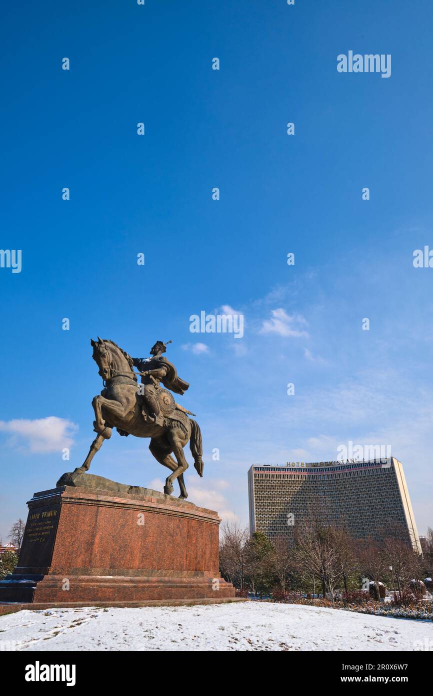 Blick auf die große Pferde- und Führungsstatue in der Mitte des Amir Temur Square Parks. Das Hotel Usbekistan im Hintergrund. Gleich nach einem Wintersturm Stockfoto
