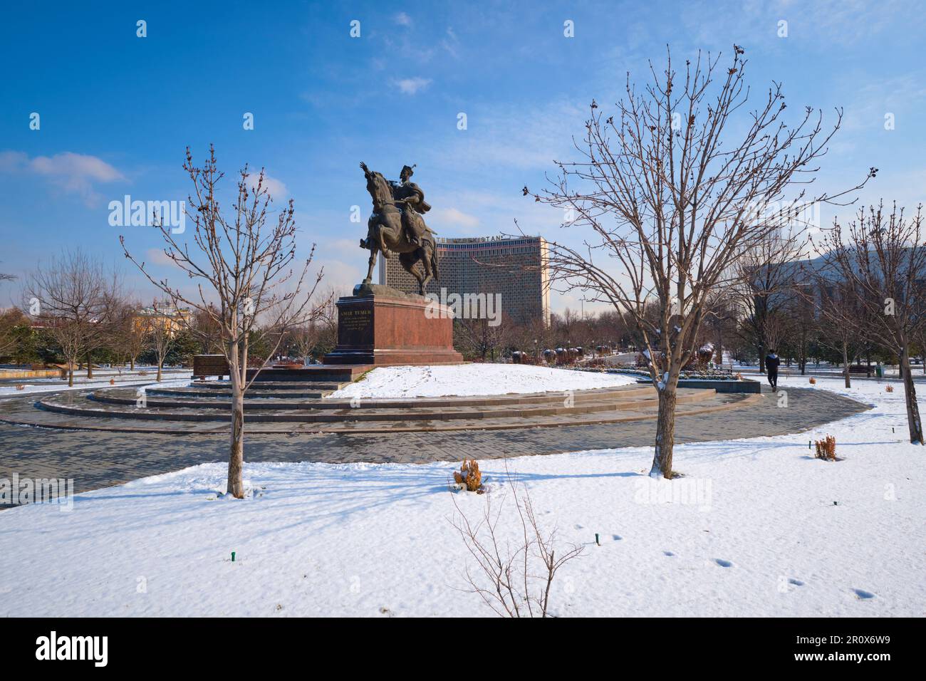 Blick auf die große Pferde- und Führungsstatue in der Mitte des Amir Temur Square Parks. Das Hotel Usbekistan im Hintergrund. Gleich nach einem Wintersturm Stockfoto