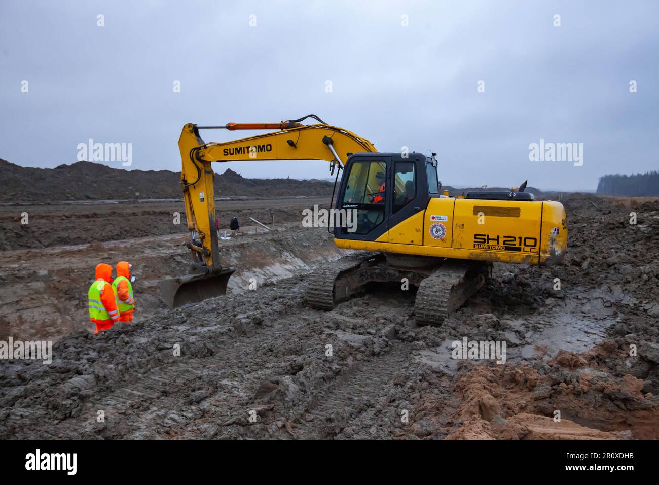 USt-Luga, Oblast Leningrad, Russland - 16. November 2021: Arbeiter machen Straßengräben mit Bagger. Bodenarbeiten über dem Regen Stockfoto