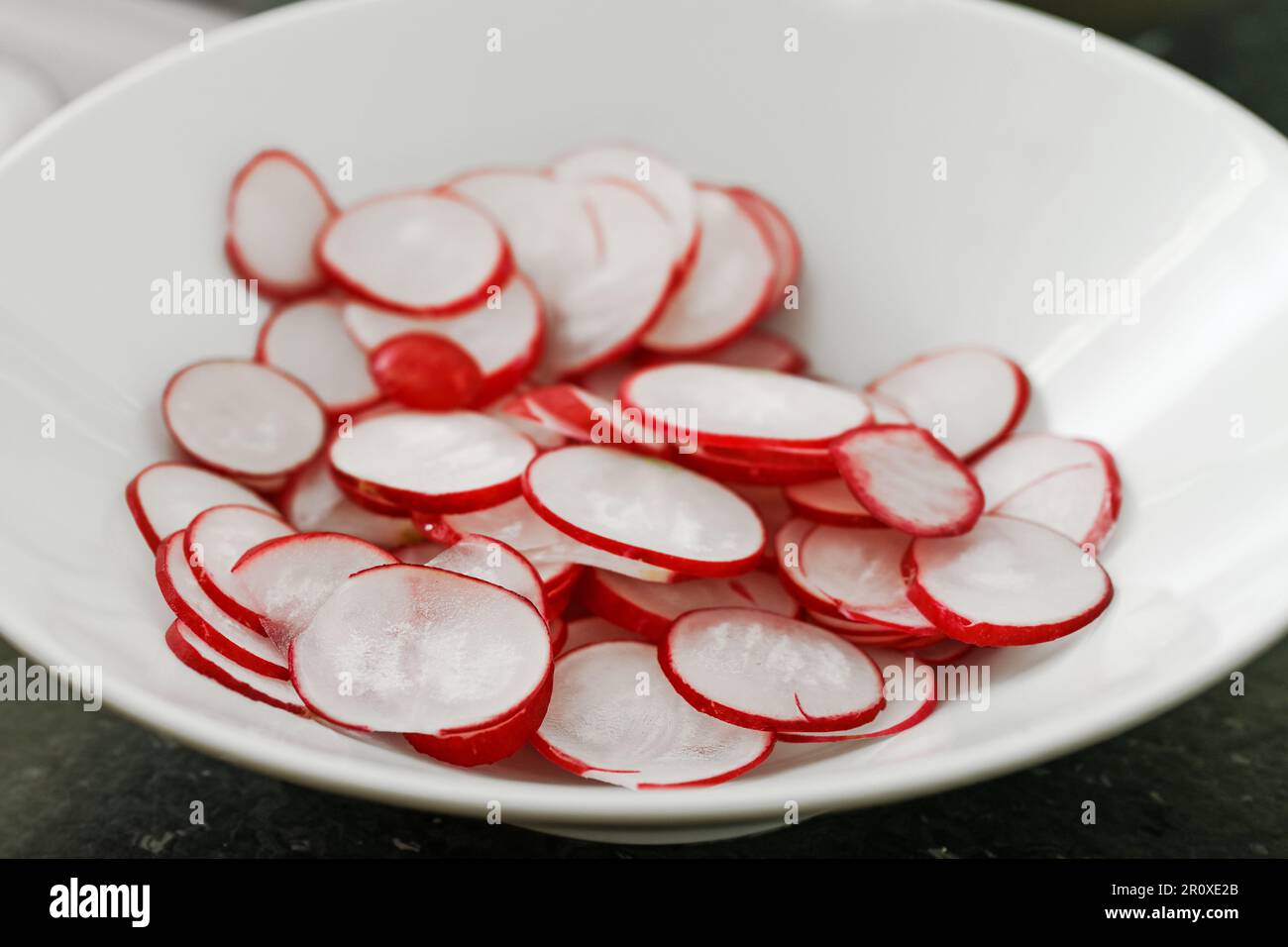 Scheiben von frischem Radieschen in einer weißen Schüssel, Kopierraum, ausgewählter Fokus, schmale Schärfentiefe Stockfoto