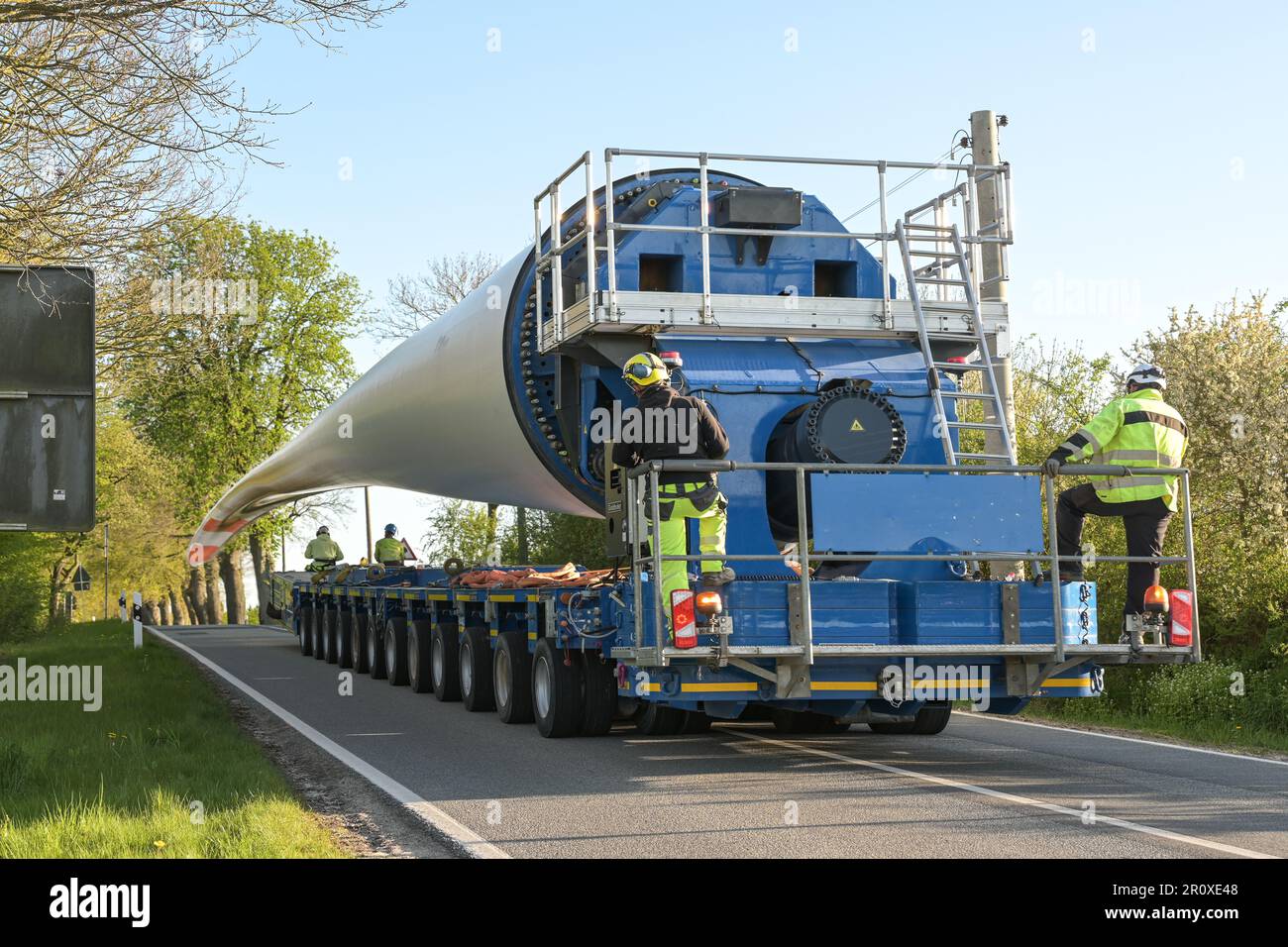 Schwerlasttransport einer Windturbinenschaufel auf einer schmalen Landstraße, Industriekonzept für Energie und erneuerbare Energien, Kopierraum, ausgewählter Fokus Stockfoto