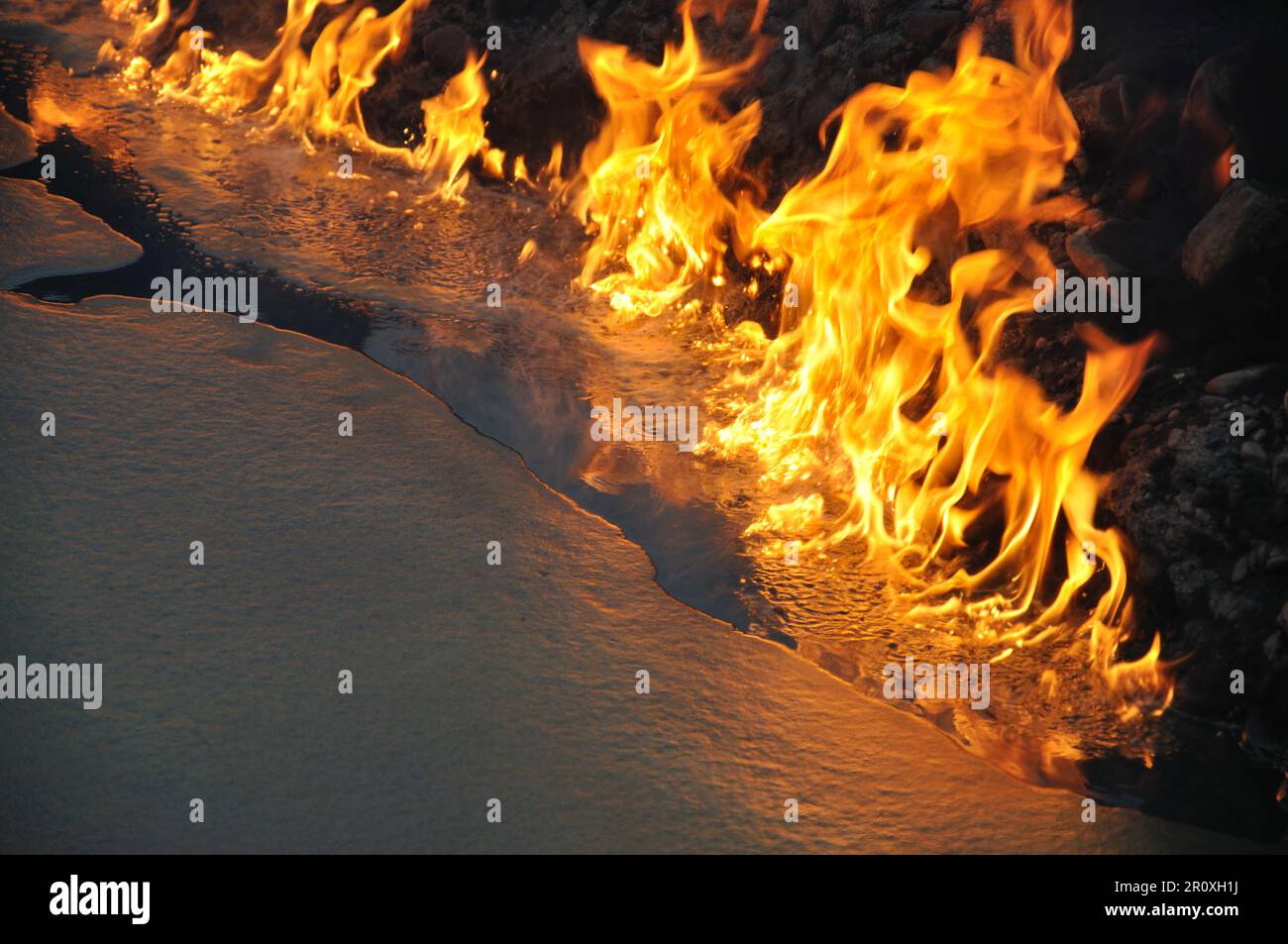 Flammen auf der Oberfläche eines öligen Teiches Stockfoto