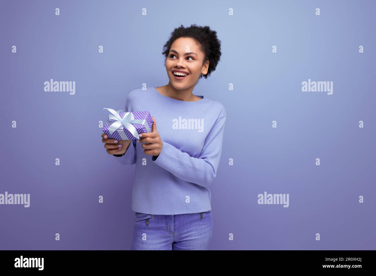 Junge brünette Frau mit Afrohaar bekam ein Geburtstagsgeschenk Stockfoto