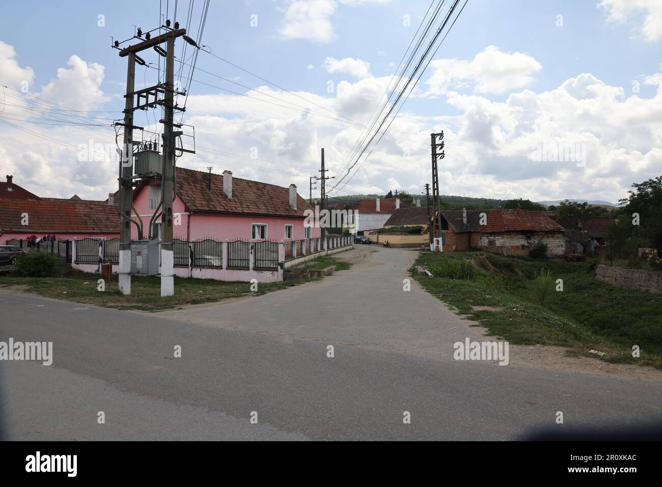 Straßenkreuzung im Dorf Câlnic, Transsylvanien, Rumänien, mit Strompylon und Stromkabeln Stockfoto