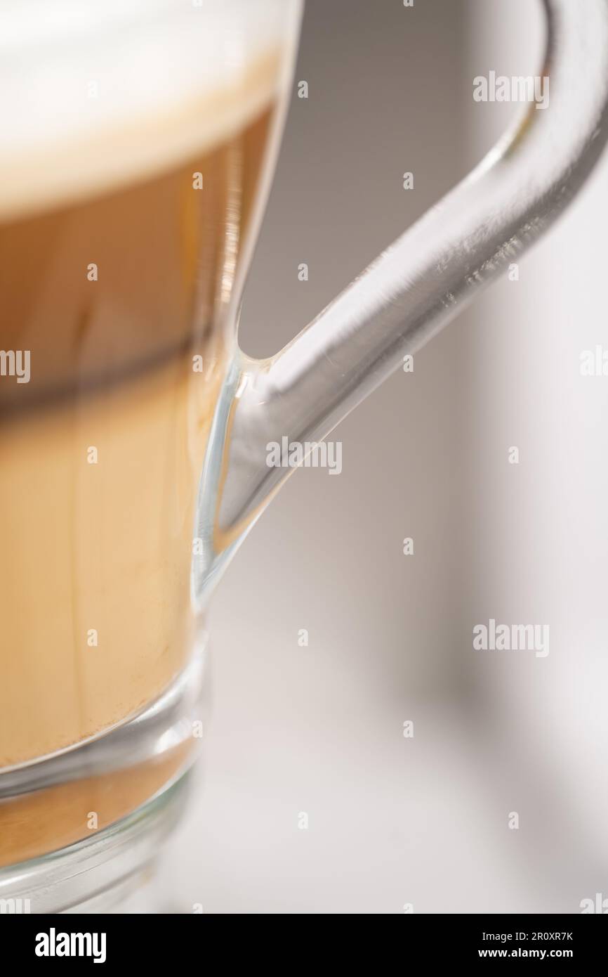 Eine Glastasse Latte Kaffee mit Milchschaum. Selektiver Fokus. Isoliert auf weißem Hintergrund. Stockfoto