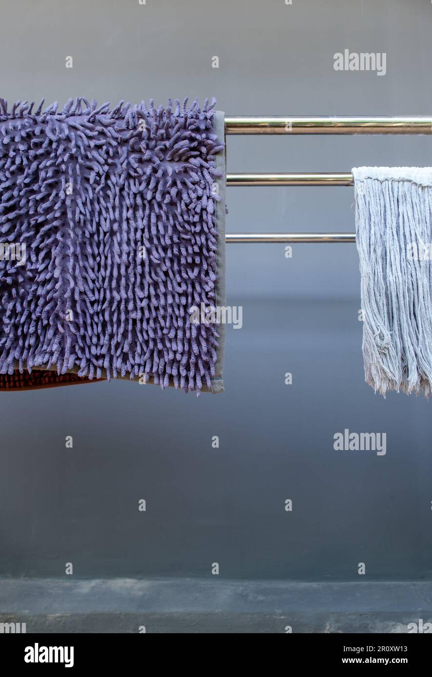 Der Reinigungsfußschaber und das Wischtuch hängen nach dem Waschen in der Nähe der Hauswand an der Metalllinie, Vorderansicht mit dem Kopierbereich Stockfoto
