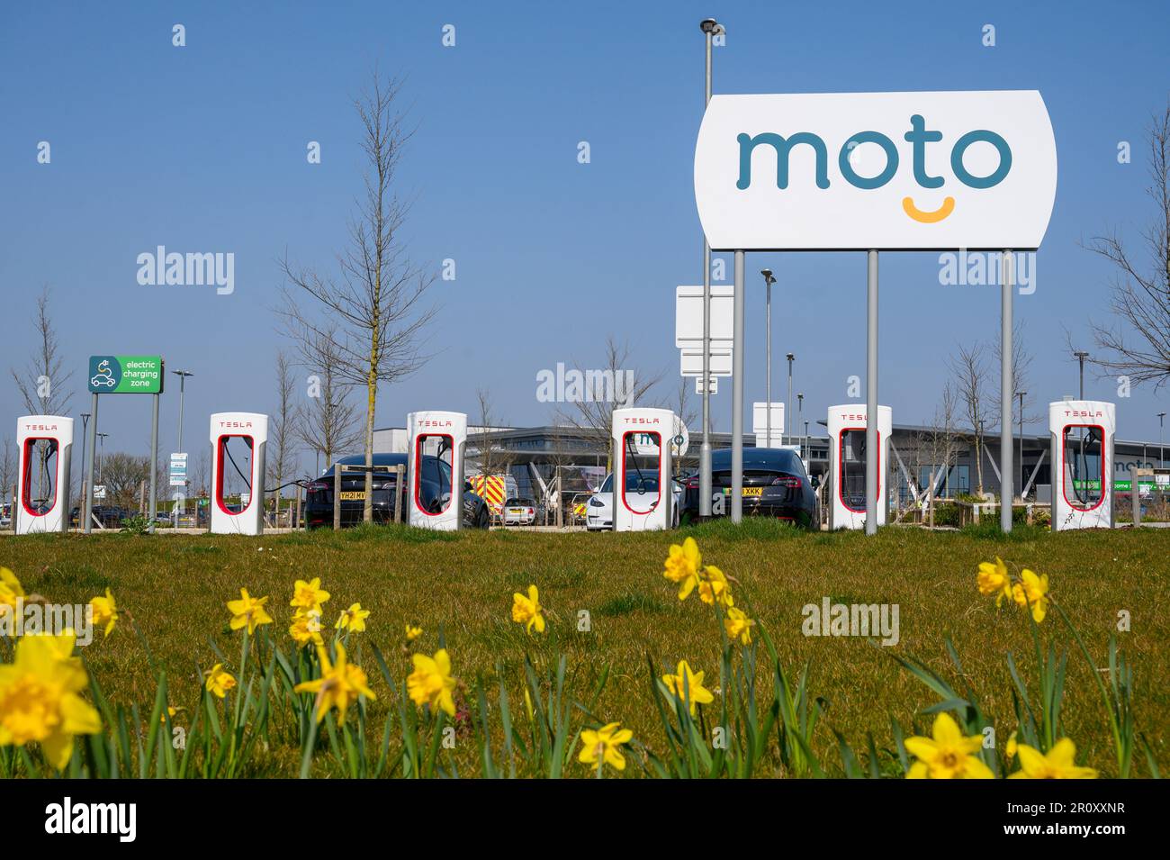 Tesla-Fahrzeuge, die an Tesla Supercharger an einer Autobahnübergabestelle in England aufgeladen werden. Stockfoto