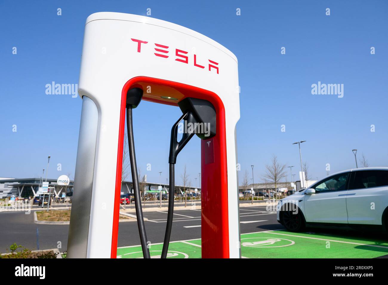 Tesla-Fahrzeuge, die an Tesla Supercharger an einer Autobahnübergabestelle in England aufgeladen werden. Stockfoto