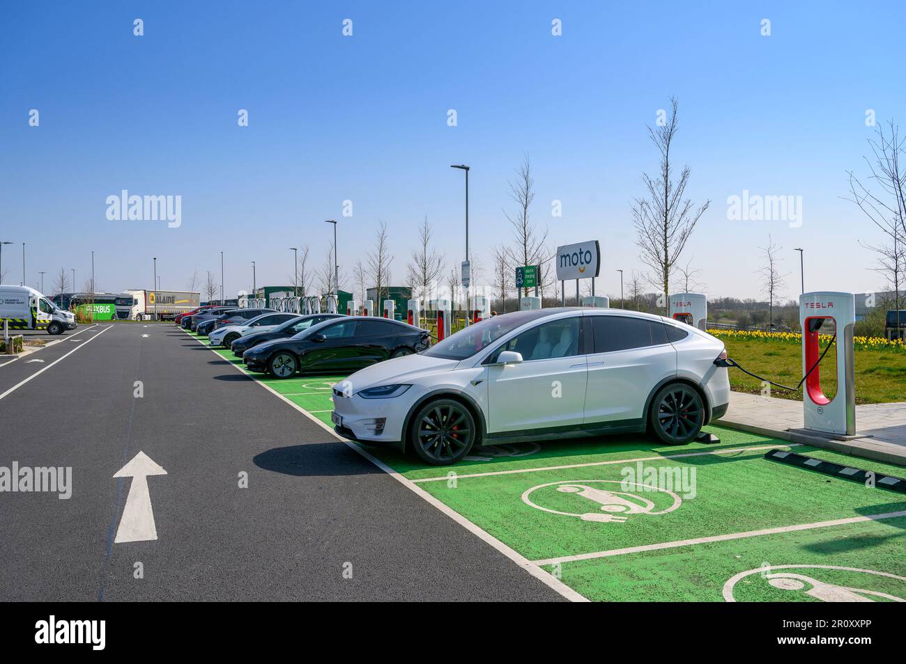 Tesla-Fahrzeuge, die an Tesla Supercharger an einer Autobahnübergabestelle in England aufgeladen werden. Stockfoto