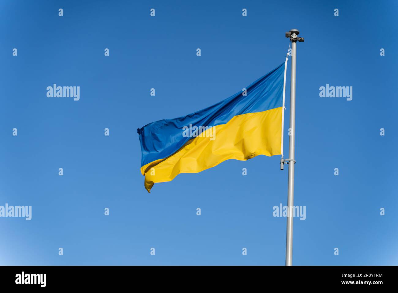 Die blau-gelbe ukrainische Flagge fliegt vor dem Hintergrund des klaren blauen Himmels. Stockfoto