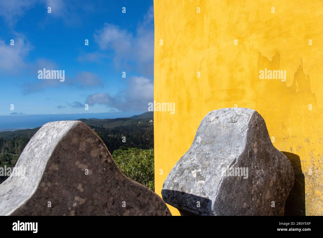 Sintra, Portugal-Oktober 2023: Nahaufnahme eines Teils der gelben Fassade und der Crenels des Nationalpalastes Pena mit grüner Landschaft im Hintergrund Stockfoto