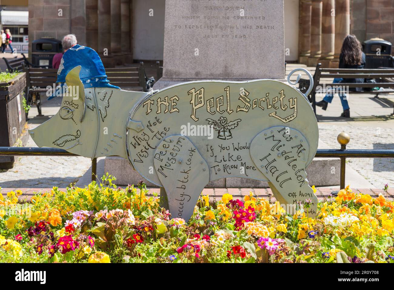 Ein Schild in Schweineform, das die Peel Society vor der Statue von Sir Robert Peel in Market Street, Tamworth, Staffordshire anzeigt Stockfoto