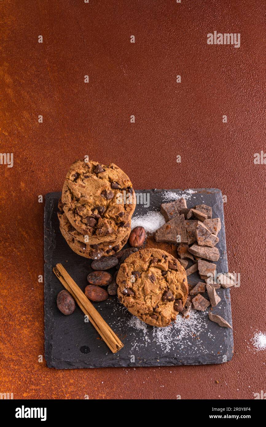 Ein kleiner Haufen Kekse mit Schokoladenstückchen. Studiofoto im rustikalen Hintergrund mit warmer Atmosphäre im Retro-Stil. Stockfoto