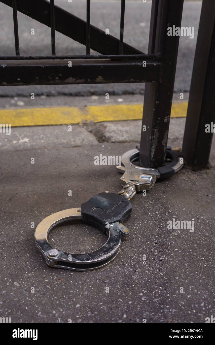 Handschellen auf dem Bürgersteig, an einem Metallgeländer auf der Straße befestigt. Paris, Frankreich. Stockfoto