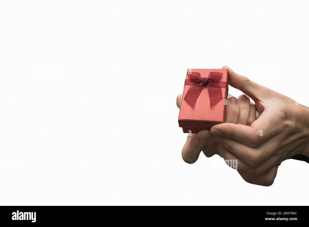 Nahaufnahme einer Person, die ein Geschenk auf weißem Hintergrund hält. Antrag oder Geburtstagsgeschenk. Stockfoto