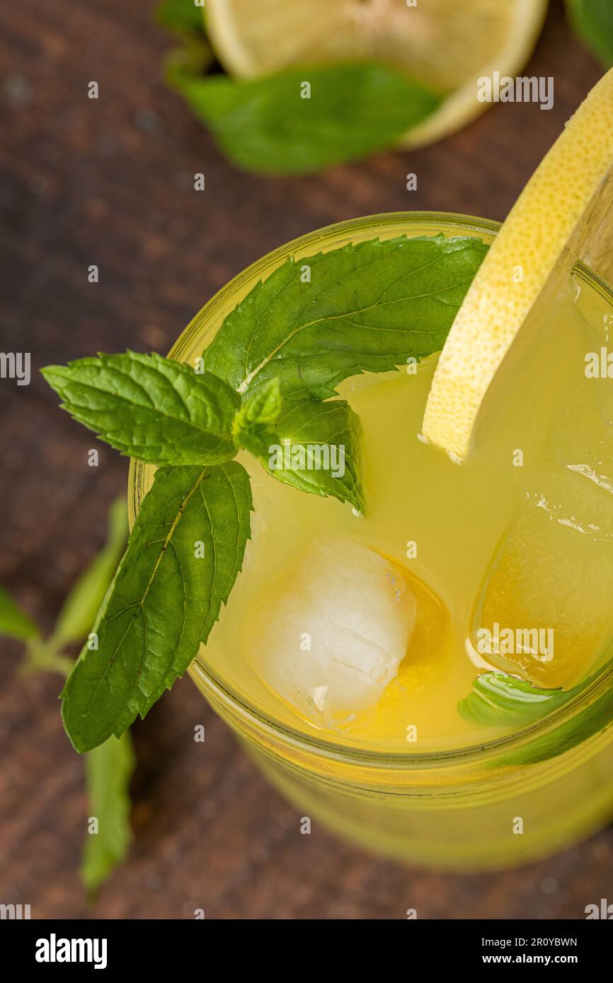 Limonade mit frischen Minzeblättern und Zitronenscheibe in Glas auf einem Holztisch Stockfoto