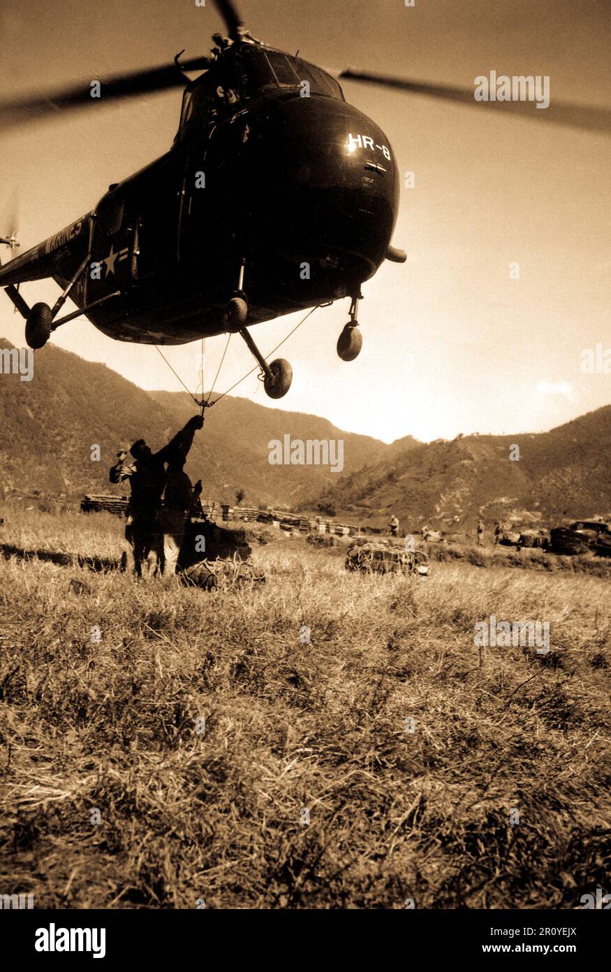 Ein HRS-1 Sikorsky Helikopter schwebt nahe am Boden, während Marines ein Frachtnetz mit 1.000 kg Vorräten anhaken, das 12 Meilen entfernt vor der Tür steht. Ca. 1951. Foto von M.Sgt. Ed. Warten Sie. (Marinekorps) Stockfoto