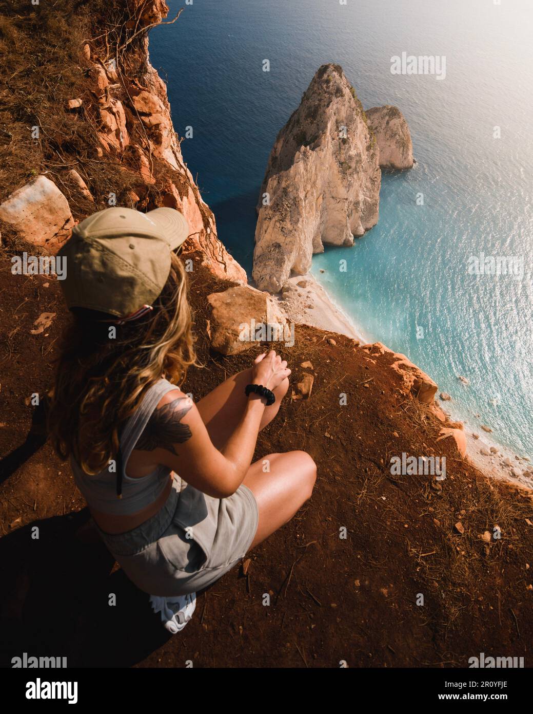 Abenteuerlustiges Mädchen, das die spektakulären Klippen und das türkisfarbene Wasser der griechischen Insel Zakhyntos während ihrer Besichtigungstour der Ionischen isl bewundert Stockfoto