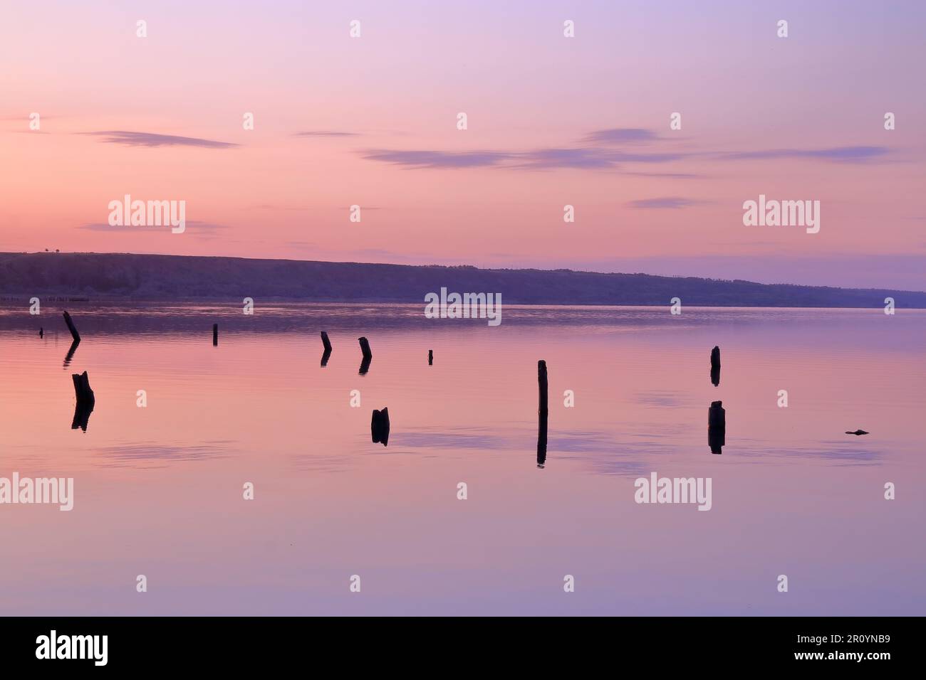 Das Foto wurde bei Sonnenuntergang in der Nähe der Mündung in der Nähe der Stadt Odessa aufgenommen. Das Spiegelbild des Wassers spiegelt die wunderschönen Farben des untergehenden Himmels wider Stockfoto