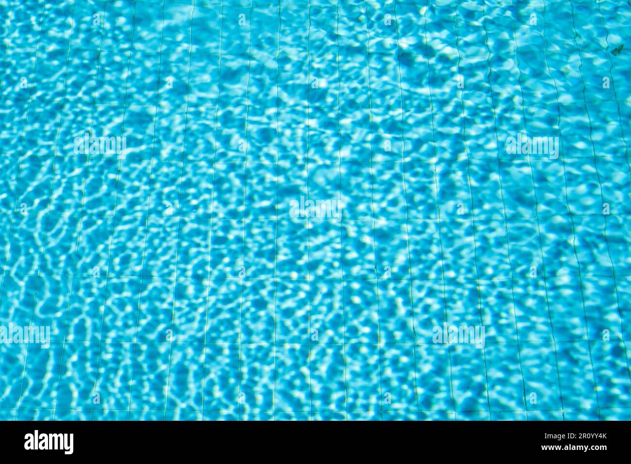 Hintergrund des Swimmingpools mit Wasser im Sonnenlicht, verschwommener Wasserhintergrund Stockfoto