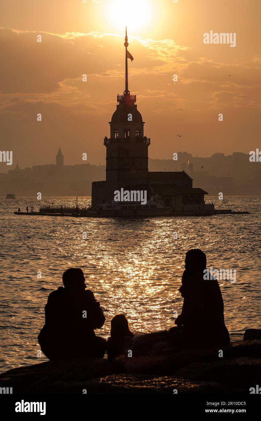 Bei einem sonnigen Sonnenuntergang beobachten die Menschen den Jungfrauenturm und den Galataturm über den Felsen. Stockfoto