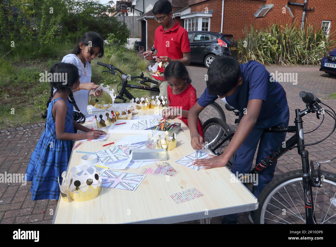 Kinder, die Kronen machen und Union Jack Flags, die König Karl III. Krönung auf der Street Party Surrey England feiern Stockfoto