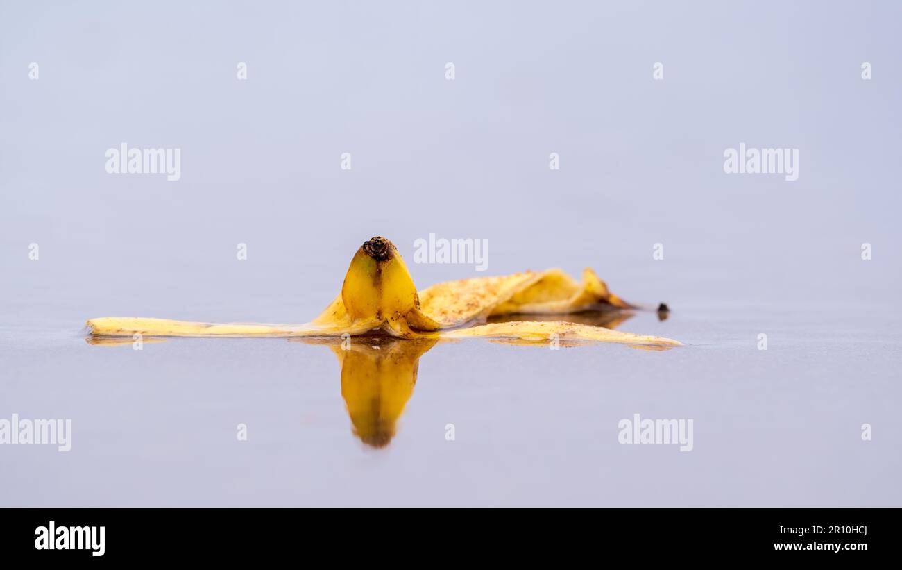 Gelbe Bananenschale liegt in nassem Sand Stockfoto