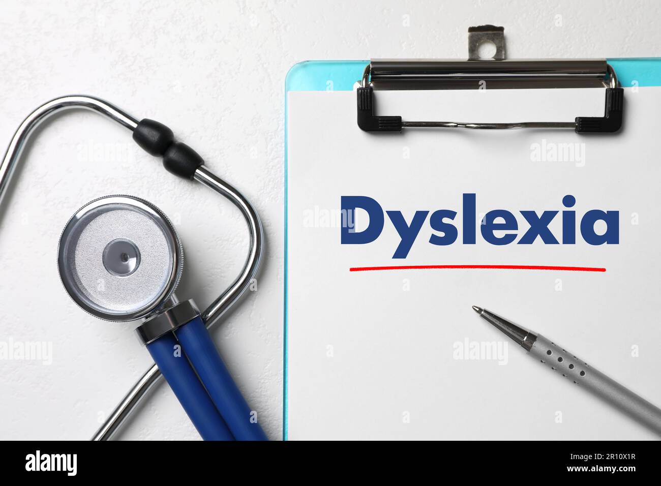 Klemmbrett mit Wort Dyslexia, Stift und Stethoskop auf weißem Tisch, flach liegend Stockfoto