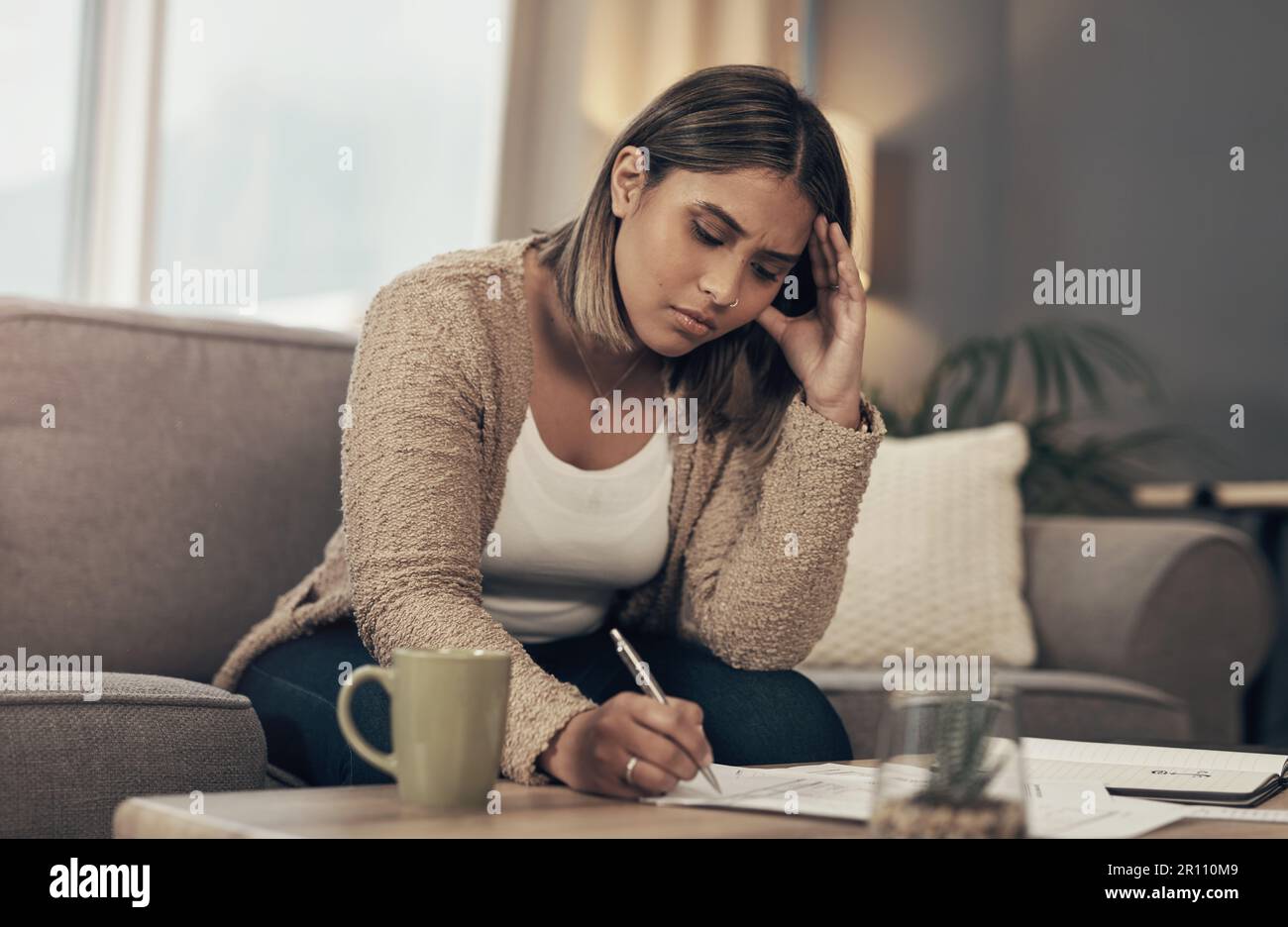 Falle nicht in die Schuldenfalle. Eine junge Frau, die gestresst aussieht, als sie zu Hause Papierkram durchging. Stockfoto