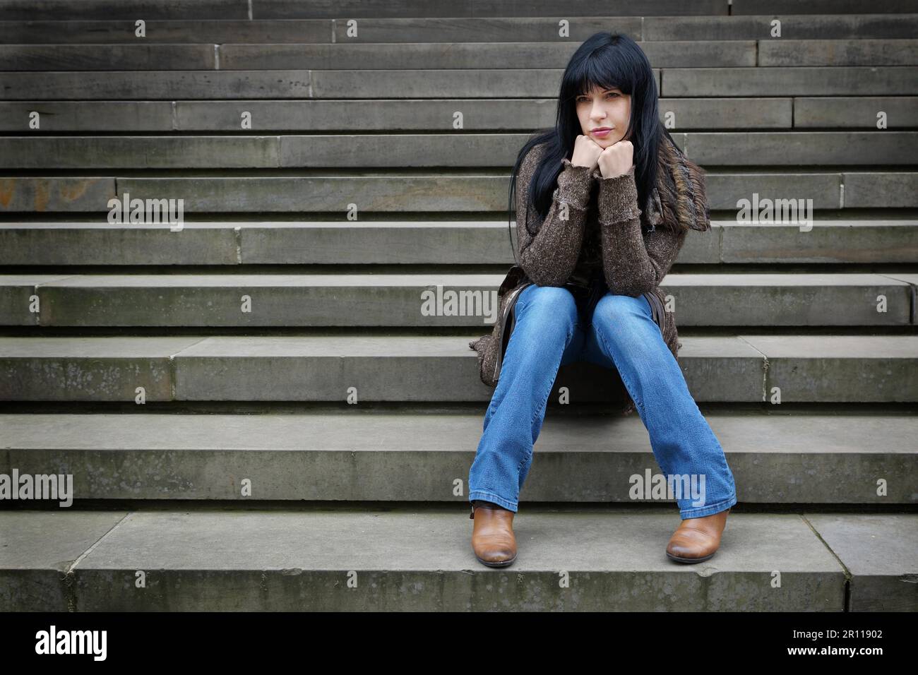 einsame Frau sitzen auf Stufen außerhalb Stockfoto