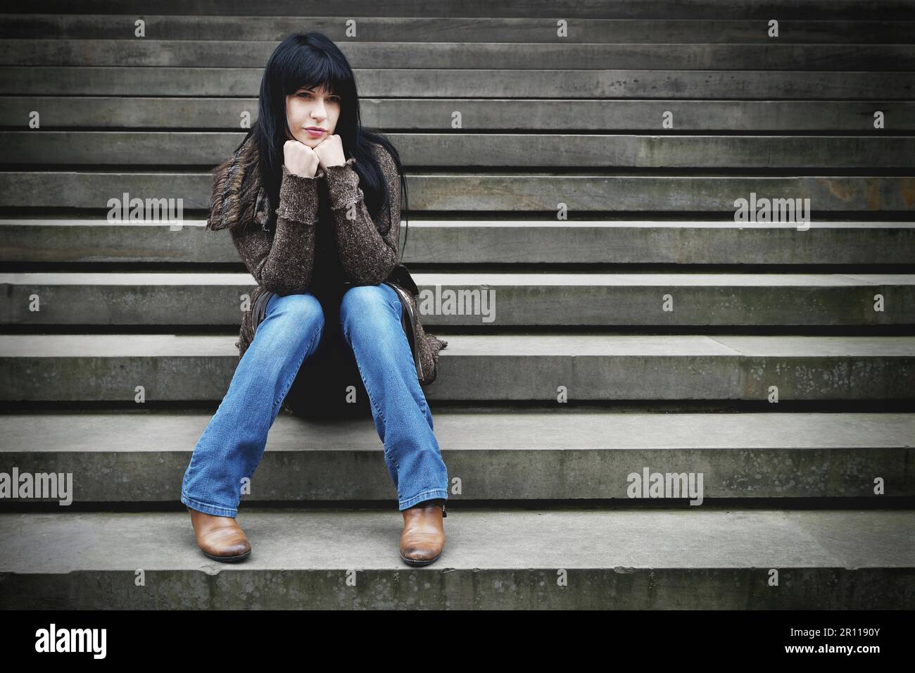 Traurige einsame junge Frau sitzt auf der Treppe mit Vintage Filterwirkung Stockfoto