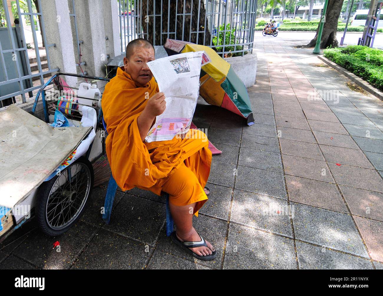 Ein thailändischer buddhistischer Mönch liest die Morgenzeitung. Bangkok, Thailand. Stockfoto