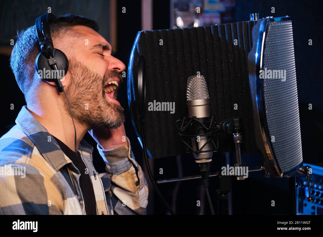 Sängerin mit Kopfhörern, die ein neues Album in einem Aufnahmestudio aufnimmt. Stockfoto